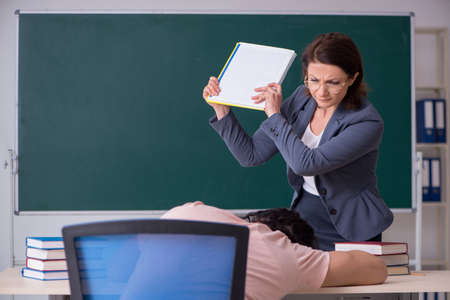 Old female teacher and male student in the classroomの写真素材