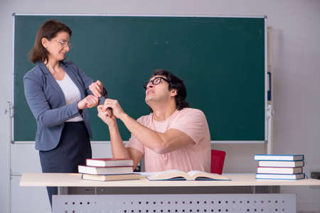 Old female teacher and male student in the classroomの写真素材
