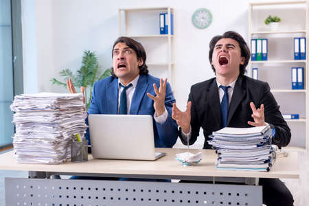 Two male colleagues unhappy with excessive workの写真素材