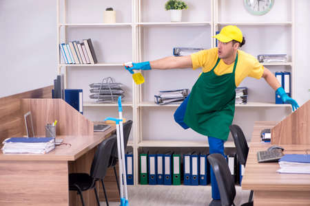 Young male contractor cleaning the officeの写真素材