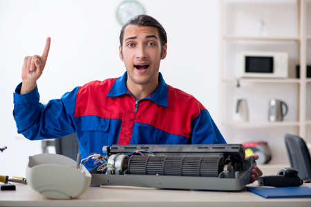 Young repairman repairing air-conditioner at warranty centerの写真素材