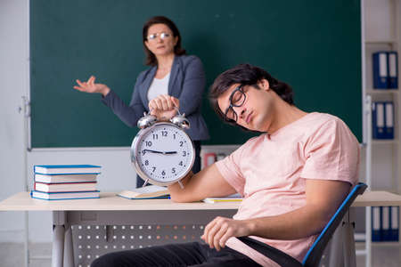 Old female teacher and male student in the classroomの写真素材