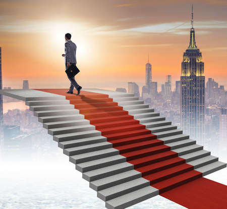 Young businessman climbing stairs and red carpetの写真素材