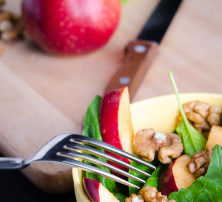 The spinach salad with nuts and apples served on tableの写真素材