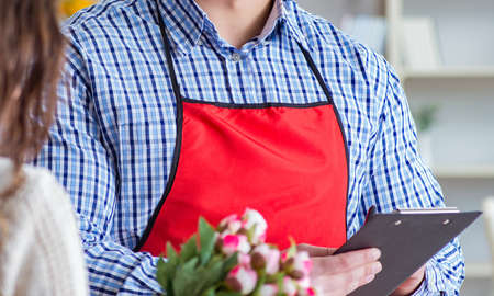 Flower shop assistant selling flowers to female customerの写真素材