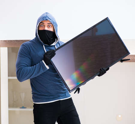 Man burglar stealing tv set from house