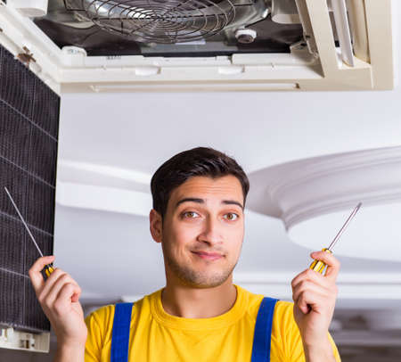 Repairman repairing ceiling air conditioning unitの写真素材