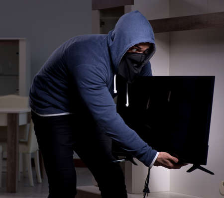 Burglar thief stealing tv from apartment houseの写真素材