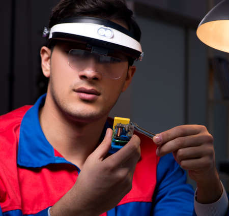 Computer specialist repairing PC late at night