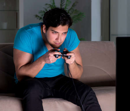 Young man playing computer games late at night