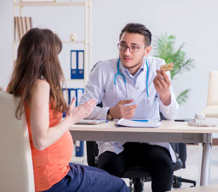 Pregnant woman with her husband visiting the doctor in clinicの写真素材
