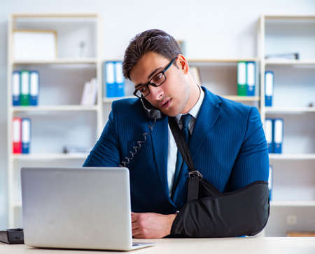 Businessman with broken arm working in officeの写真素材
