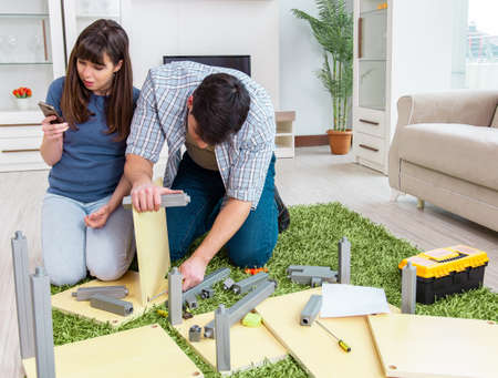 Young family assembling furniture at new houseの写真素材