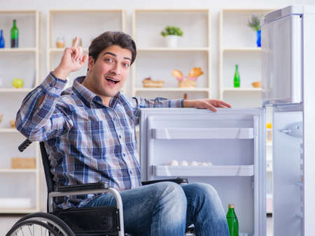 Young disabled injured man opening the fridge doorの写真素材