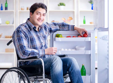 Young disabled injured man opening the fridge door