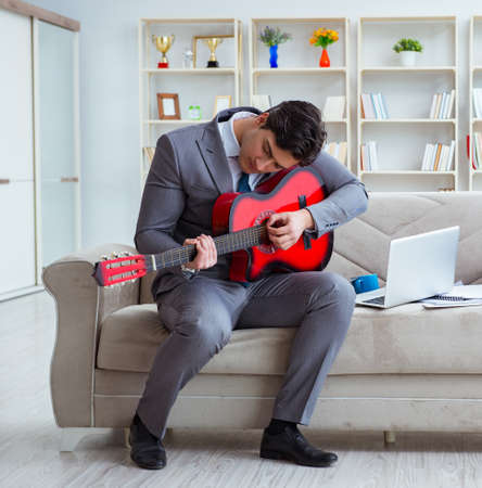 Businessman playing guitar at homeの写真素材