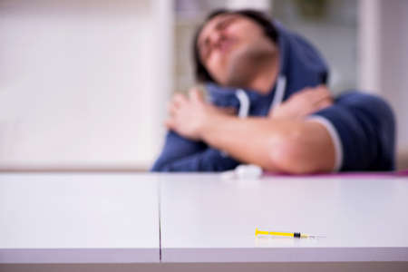 Young man having problems with narcotics at homeの写真素材