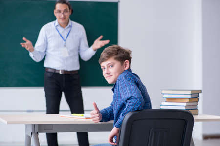 Young male teacher and boy in the classroomの写真素材