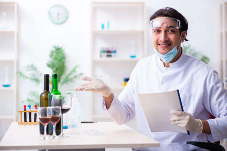 Male chemist examining wine samples at lab