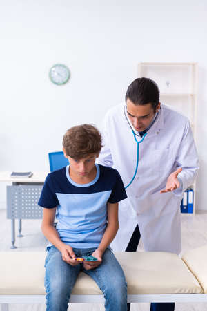 Young male doctor examining boy in the clinicの写真素材