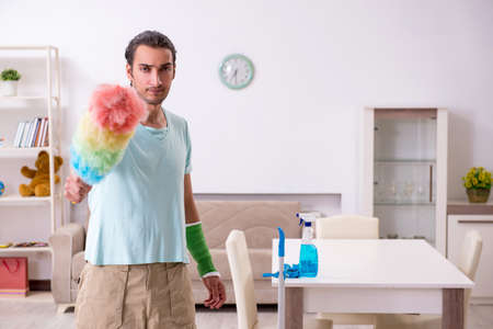 Young injured man cleaning the house