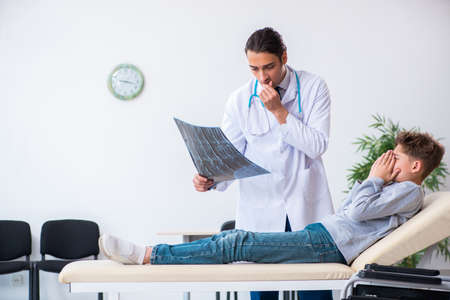 Young male doctor pediatrist and boy in wheel-chairの写真素材
