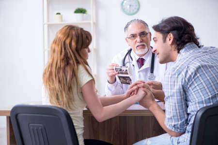 Young couple visiting old male doctor