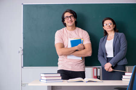 Old female teacher and male student in the classroomの写真素材