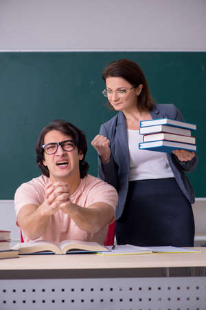 Old female teacher and male student in the classroomの写真素材