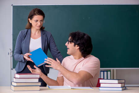 Old female teacher and male student in the classroomの写真素材