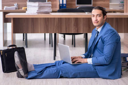 Young male employee and too many work in the officeの写真素材