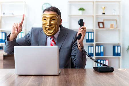 Businessman wearing mask in hypocrisy conceptの写真素材