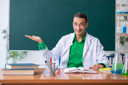 Young male chemist teacher in front of blackboardの写真素材