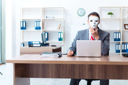 Businessman wearing mask in hypocrisy conceptの写真素材