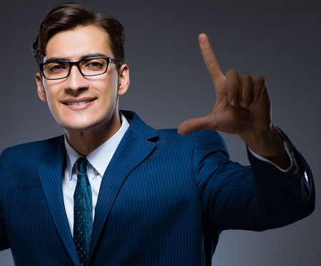 Businessman pressing virtual buttons on gray backgroundの写真素材
