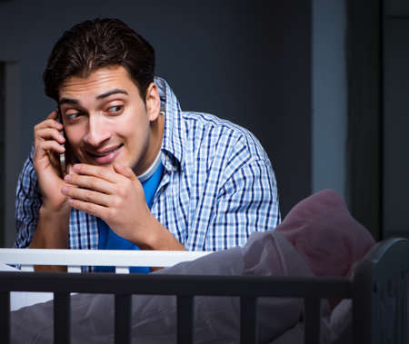 The happy dad looking after newborn baby at nightの写真素材