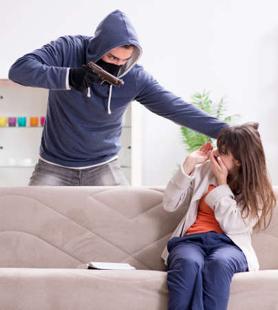 Armed man assaulting young woman at homeの写真素材