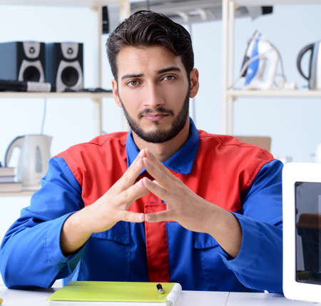 Young repairman fixing and repairing microwave oven