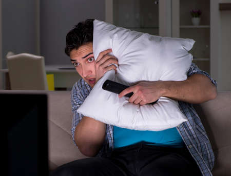 Young man watching tv late at nightの写真素材