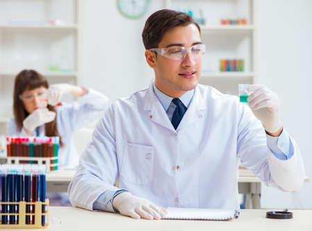 Two chemists working in lab experimentingの写真素材