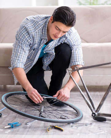 Young man repairing bicycle at homeの写真素材