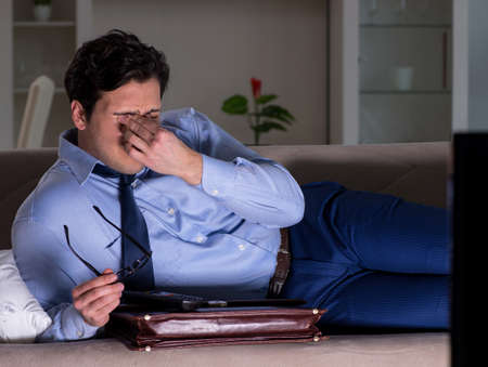 Businessman watching tv at night lateの写真素材