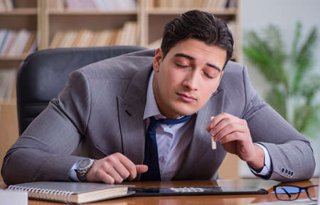 Drug addict businessman in the officeの写真素材
