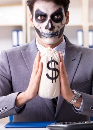 Businessmsn with scary face mask working in officeの写真素材