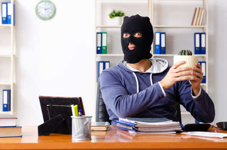 Male thief in balaclava in the officeの写真素材