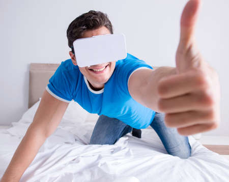 Young man in bed wearing a vr virtual reality head setの写真素材