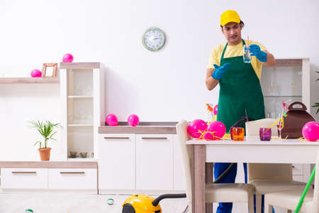 Young male contractor doing housework after partyの写真素材