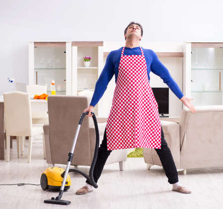 Young man vacuum cleaning his apartmentの写真素材