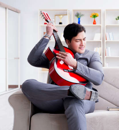 Businessman playing guitar at homeの写真素材