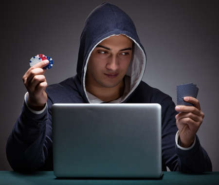 Young man wearing a hoodie sitting in front of a laptop computerの写真素材